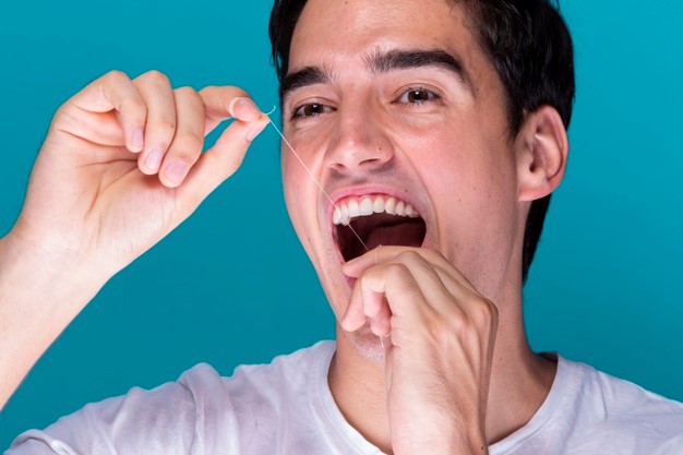 A man holding opening his mouth and holding a dental floss vertically