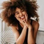 A curly haired woman sitting and smiling