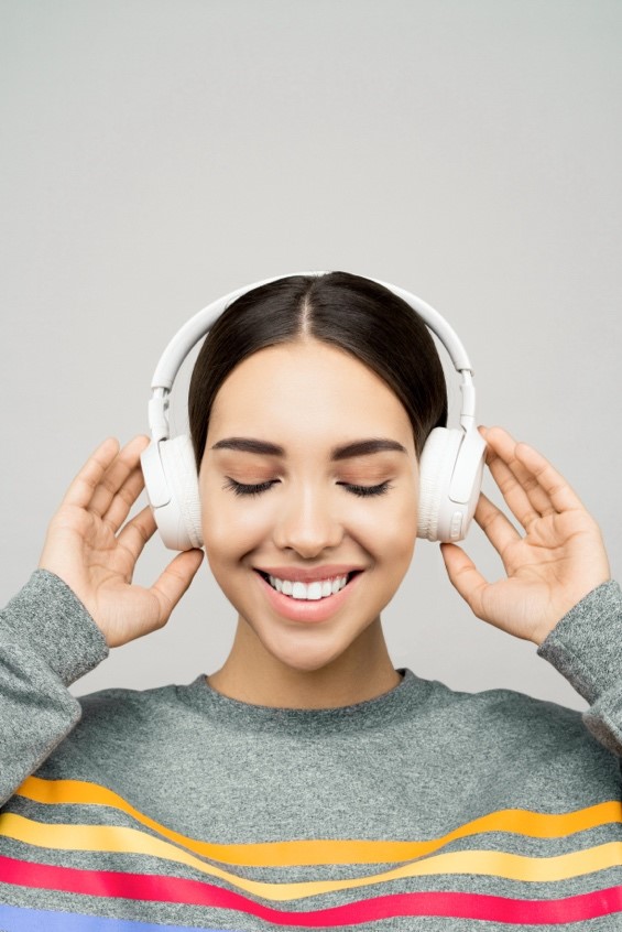 Woman in gray top wearing white headphones