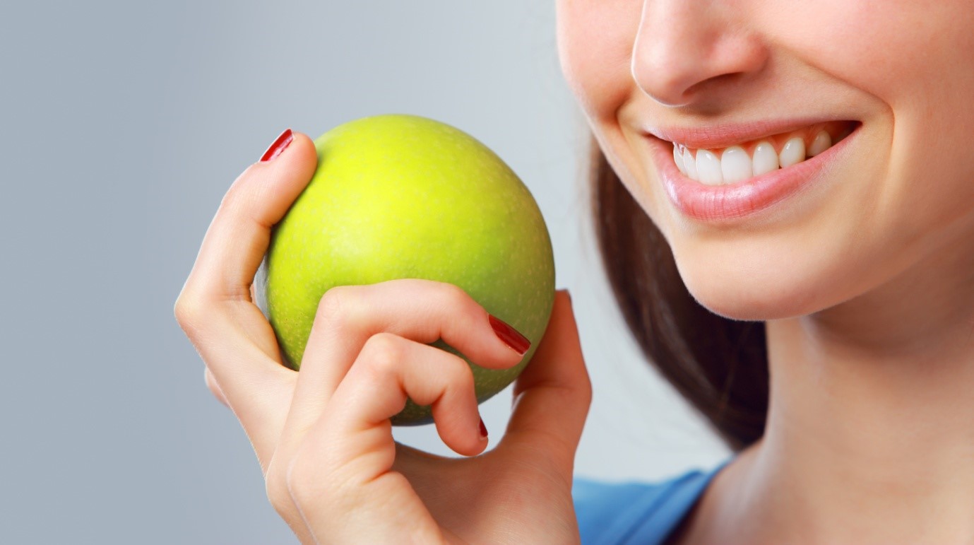 a woman holding a green apple and grinning