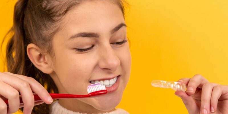A girl holding a toothbrush with whitening toothpaste over it