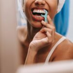 Reflection of a woman flossing her teeth