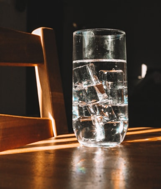A glass of iced water on a wooden table.