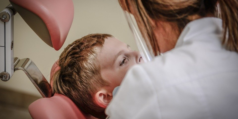 A pediatric dentist inspecting a child’s teeth