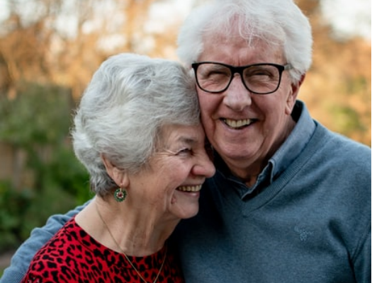 An elderly couple hugging and smiling