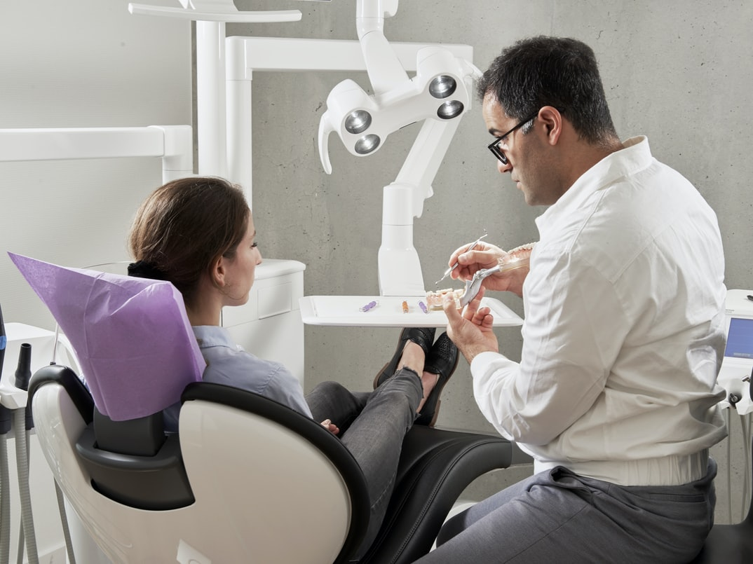 A woman in a dentist chair talking to a dentist